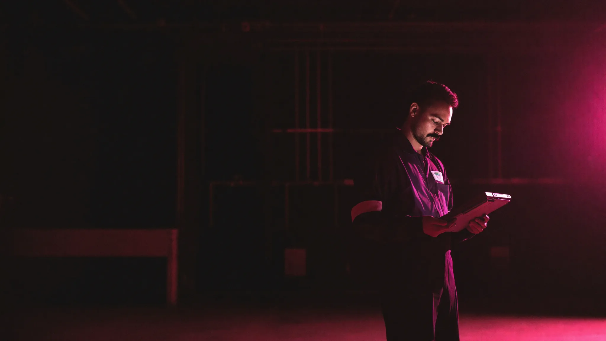An HVAC technician reading a rugged tablet, lit in magenta