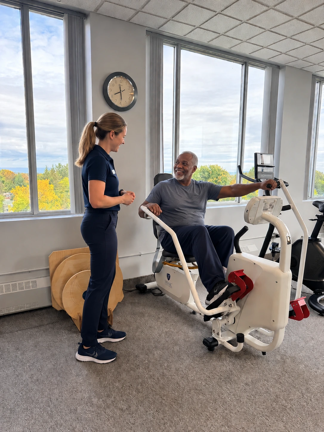 A therapist guiding a patient on a recumbent trainer