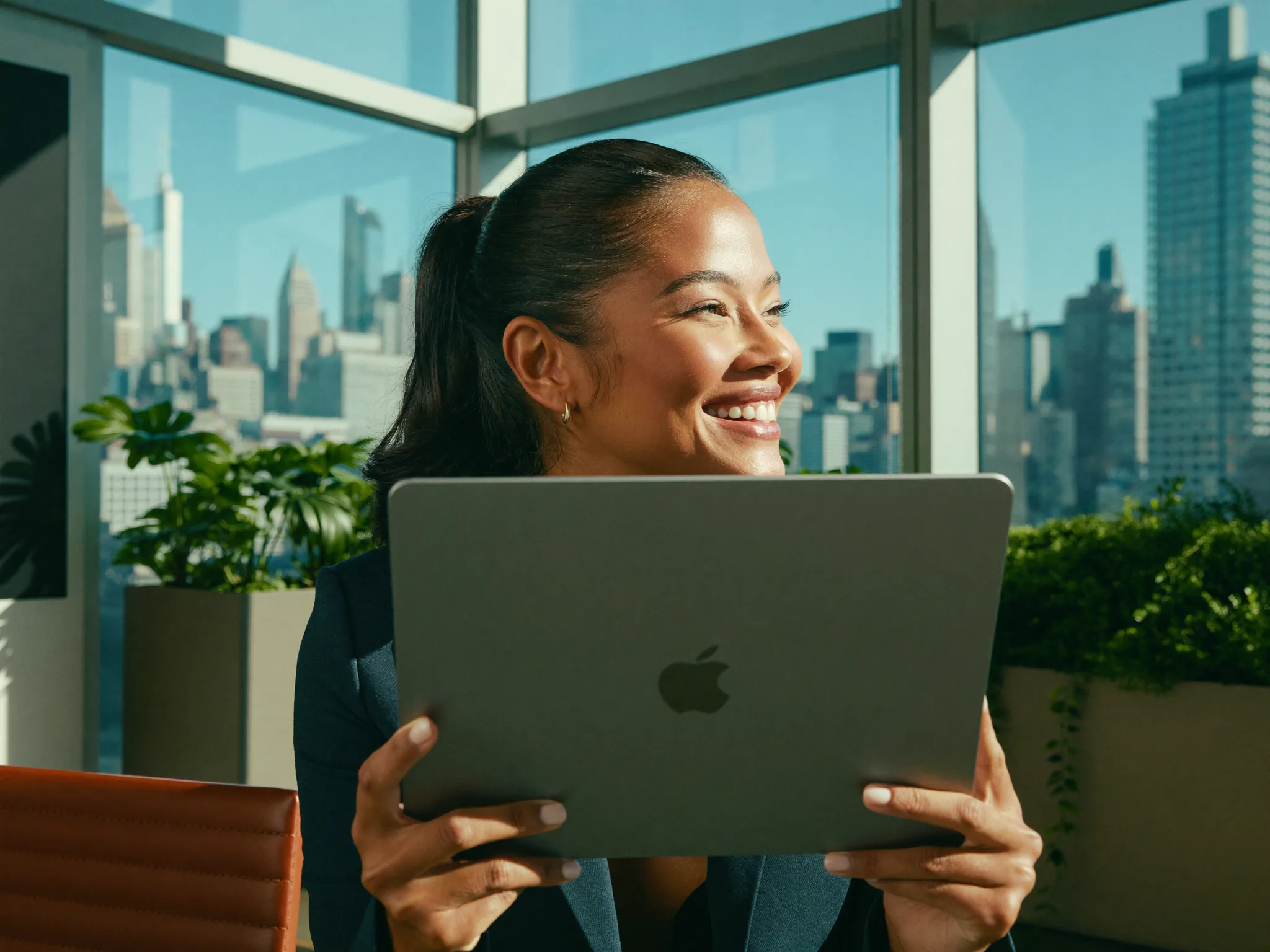 Happy broker holding a tablet and smiling by a bright office window