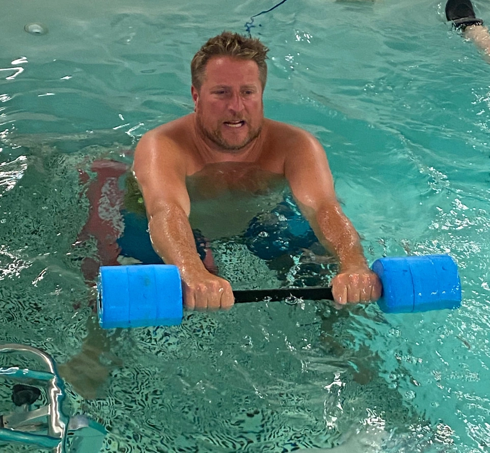 A patient pushing a water dumbbell against the resistance of the water