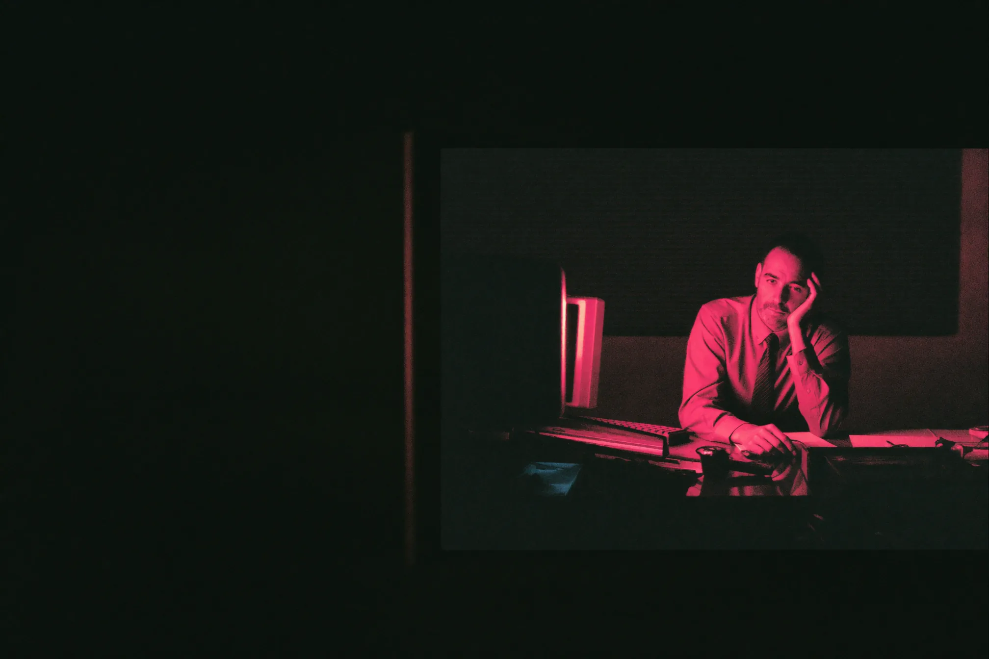 A trades business owner alone at a cluttered desk late at night with a stack of paperwork
