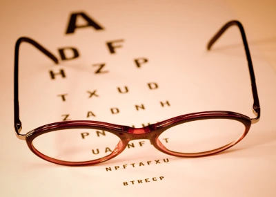 Glasses resting in front of an eye chart
